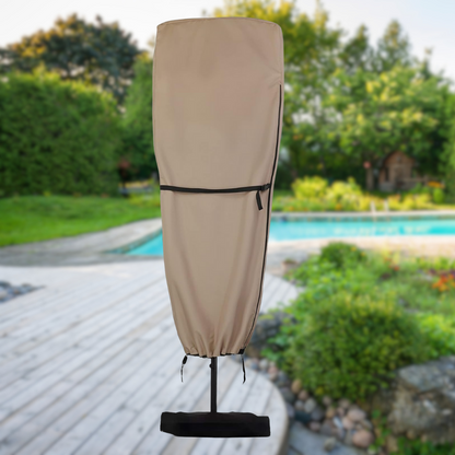 Beige patio umbrella cover with black accents on a patio with a pool and greenery in the background